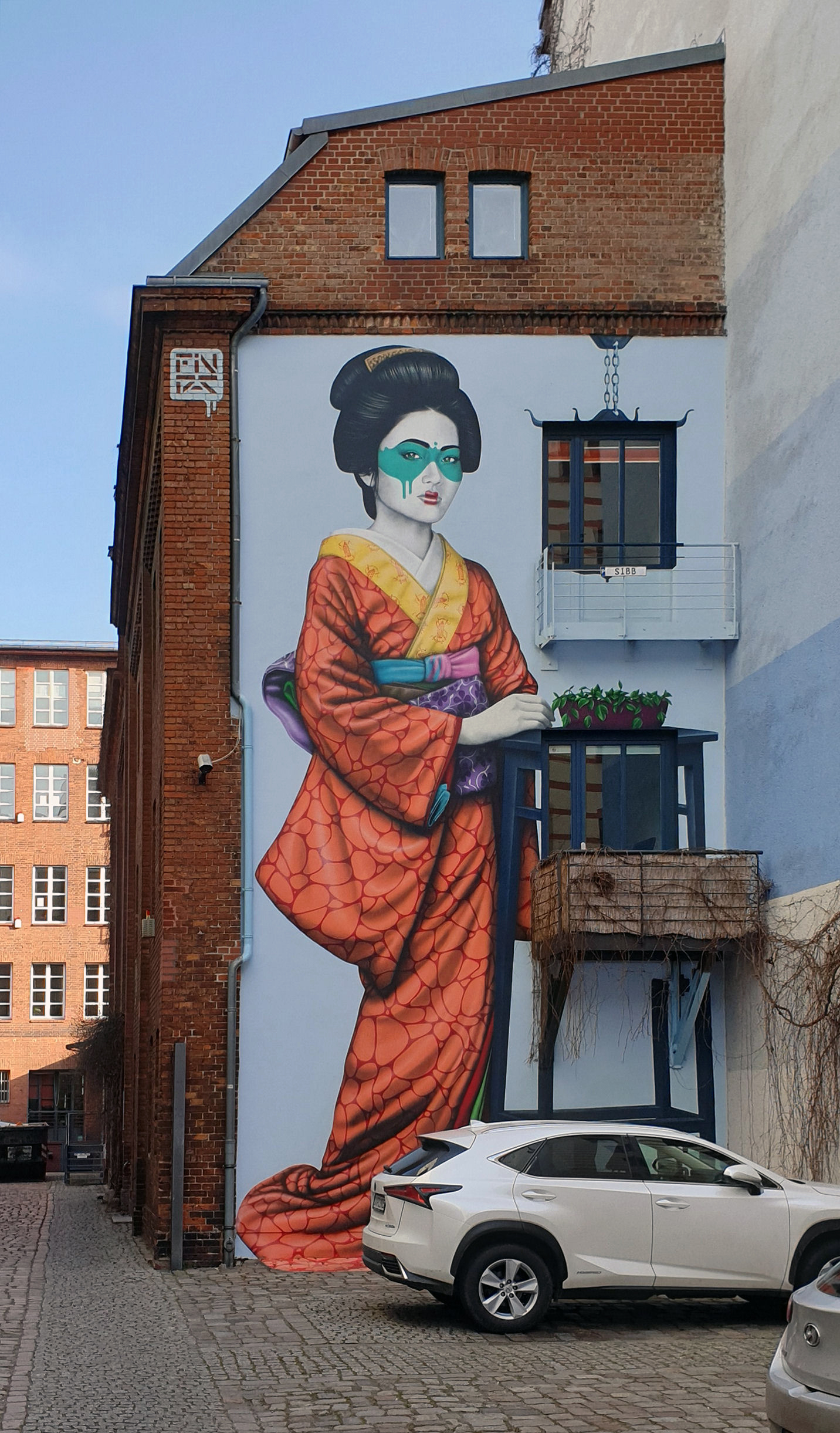Engeika, Fin DAC’s 2019 Berlin mural of a woman in an orange robe and turquoise eye mask, integrated into a building facade.