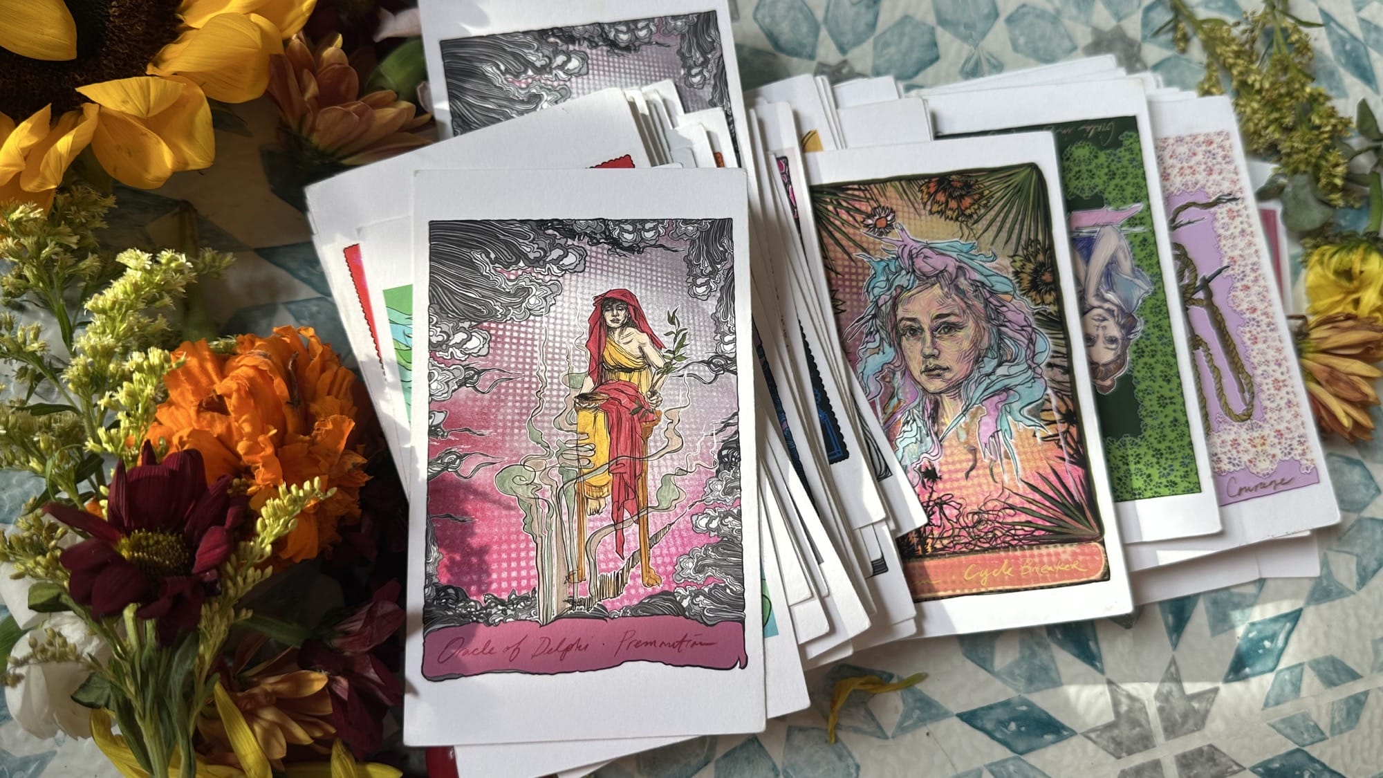 Cards from Swoon’s Sibylant Sisters Oracle Deck, arranged among flowers.