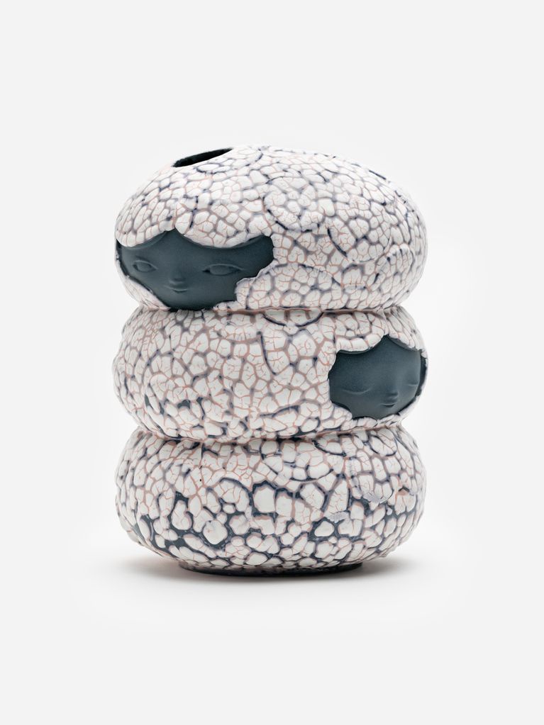 James Jean’s Blossom Vessel, with stacked pale crackled ceramic forms and dark faces emerging through the glaze.
